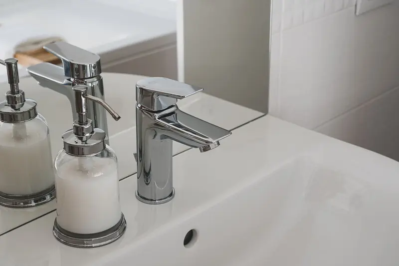 White basin with a chrome tap and soap dispenser