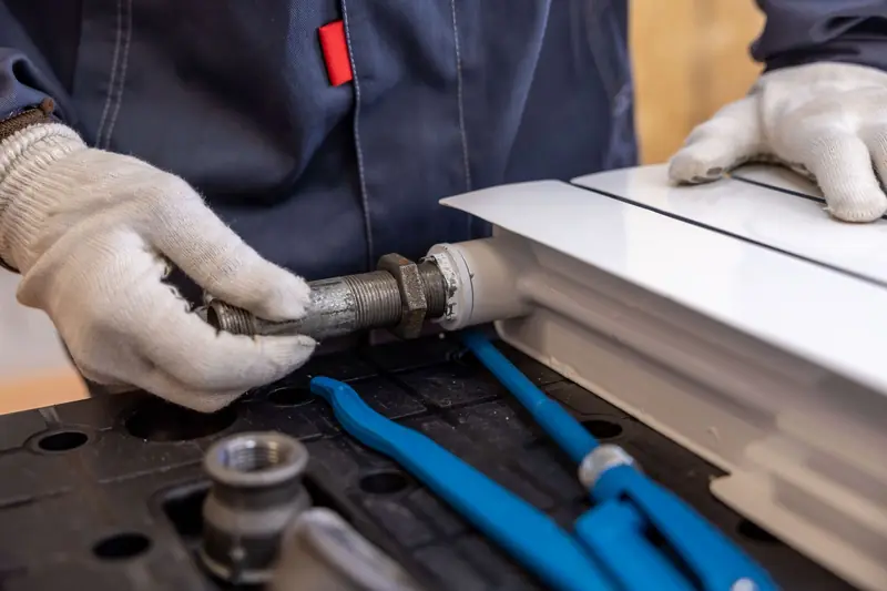 Plumber fitting a pipe connection with gloved hands